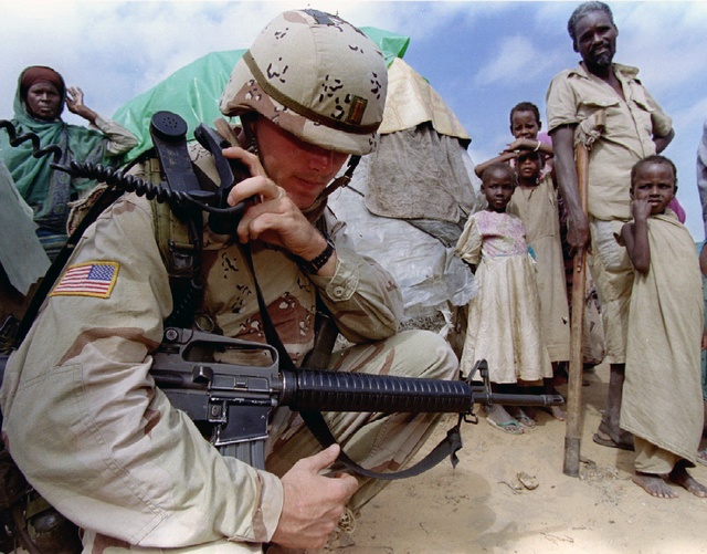 A U.S. soldier radios base, watched by displaced villagers, Mogadishu Image courtesy of: REUTERS/Dan Eldon  (SOMALIA)